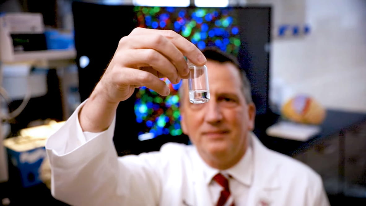 bruce lamb looks at a sample as he holds it up to the light