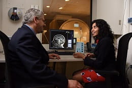 Two people in discussion in front of brain image on monitor