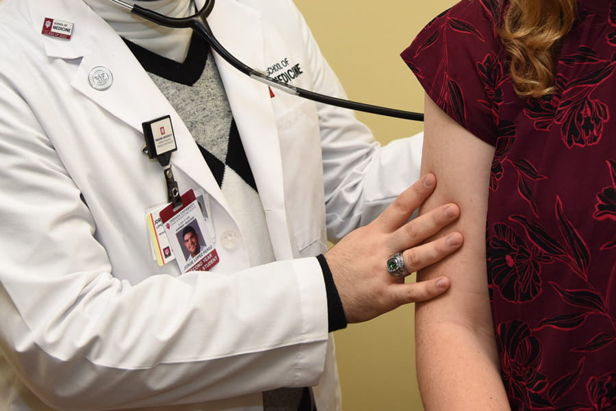 a gentle hand is placed on a patient during a visit in the clinic