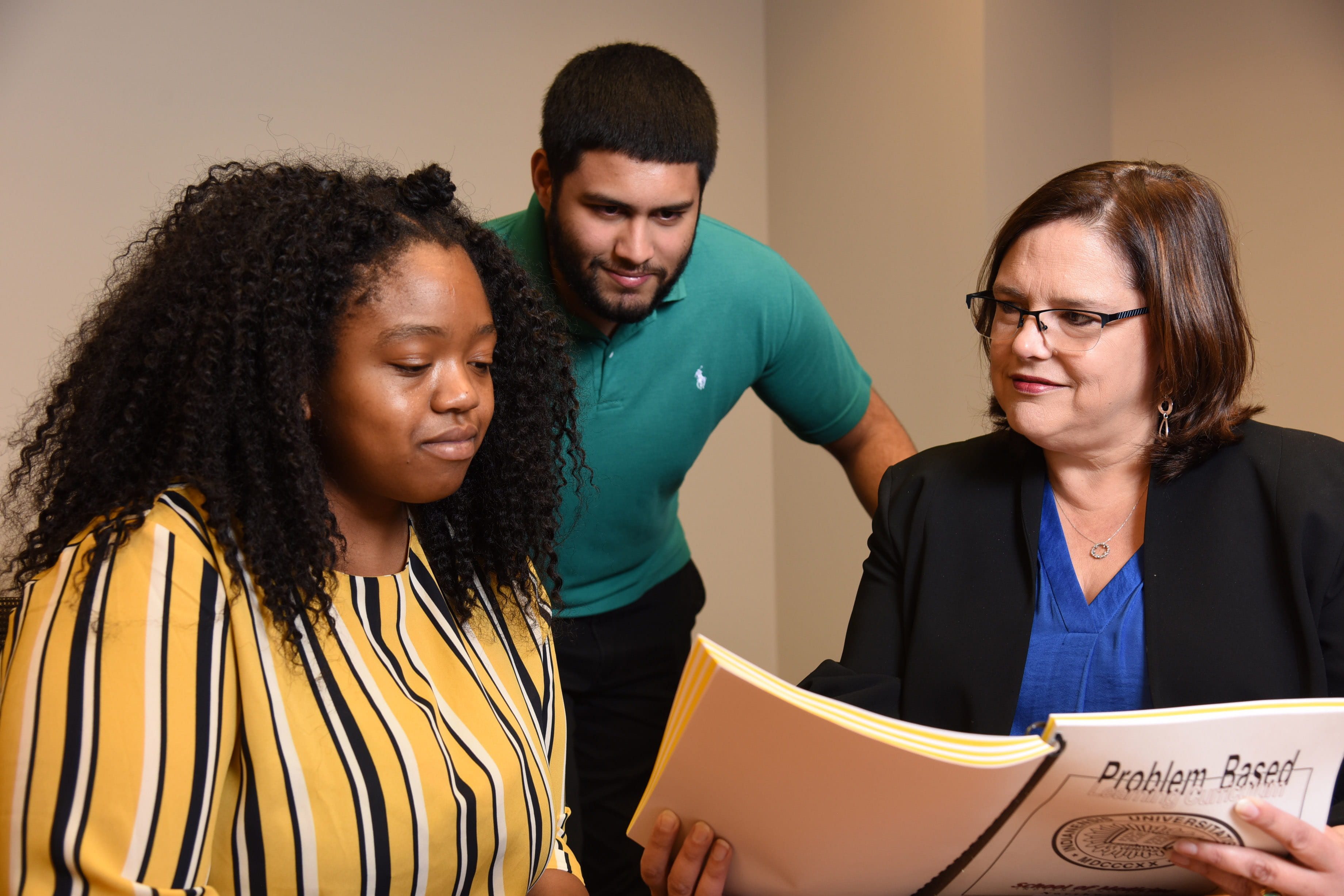 Faculty member showing two medical students a course textbook