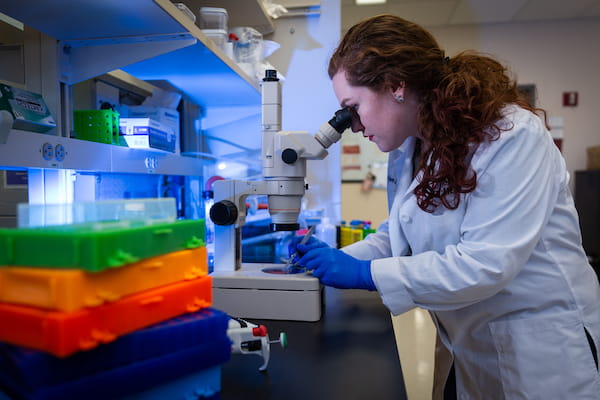 Alyson Essex looks at a sample in a microscope