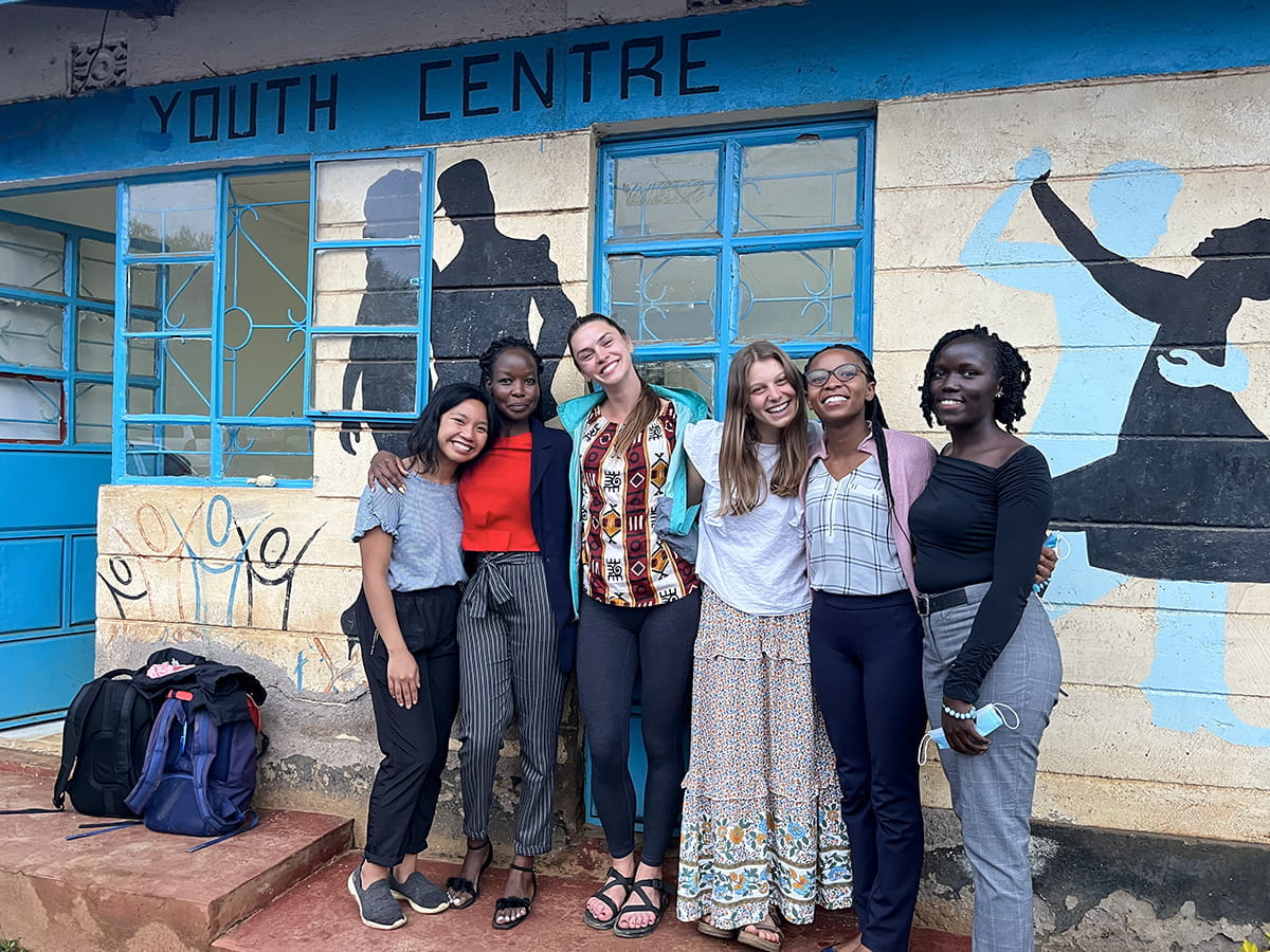 Three IU medical students with their colleagues in Kenya in front of a youth center. 