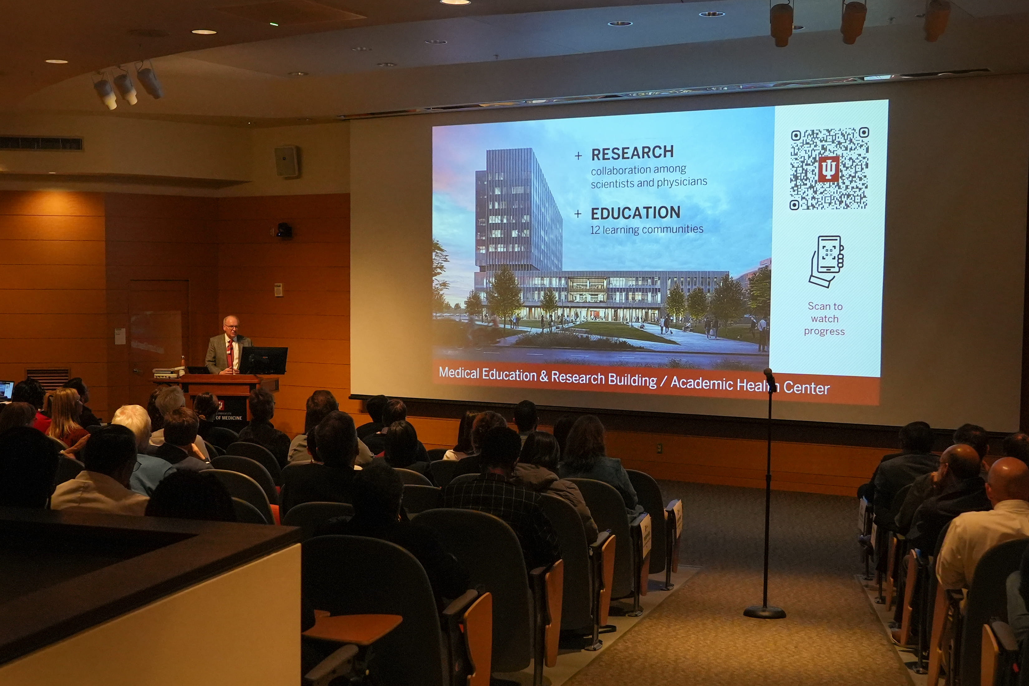 dean jay hess speaks at the all school meeting in front of a projector screen