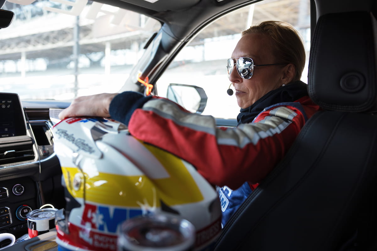 Melissa McCarthy, in fire suit, rides inside the medical response vehicle, with her helmet in the foreground of photo