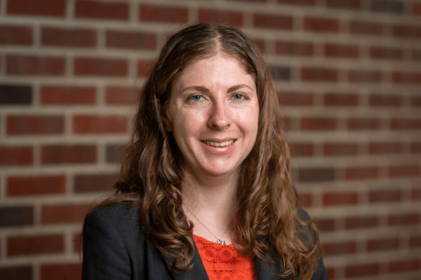 Creecy smiles for her photo in front of a brick wall