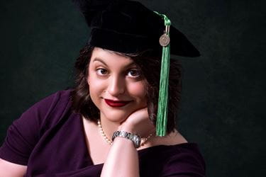 Hannah Kline in her graduation cap with green tassel, black formal background