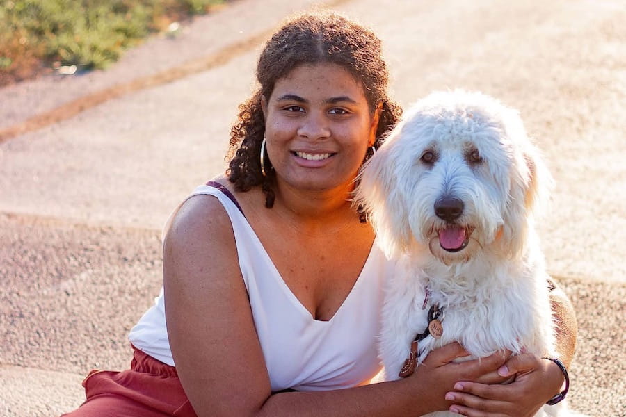 Kennedy Onuoha and goldendoodle Aura sit outside in the sunshine.