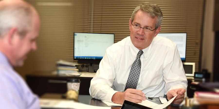 Dr Koch at his desk speaking with a colleague