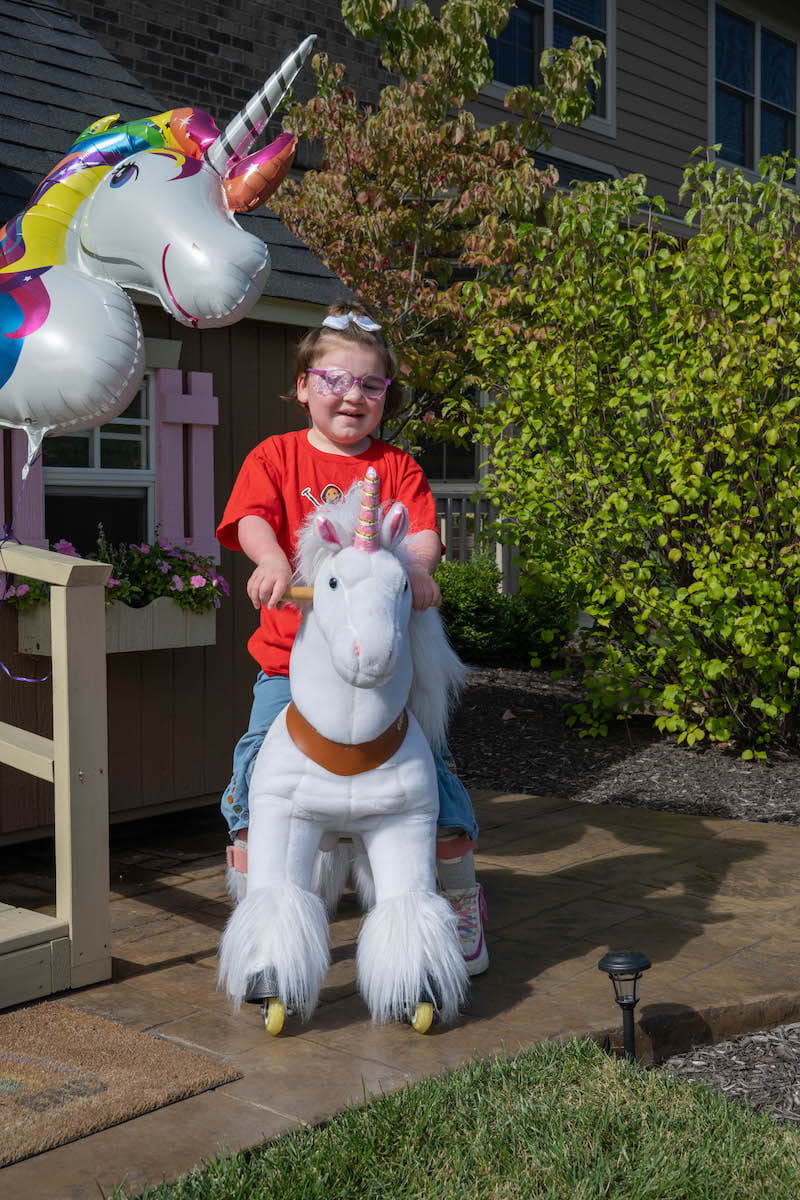 Londyn Hoffman sits on a stuffed unicorn