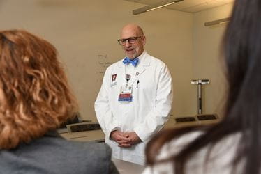 Dr. Peipert, wearing white coat, talks to learners in a classroom