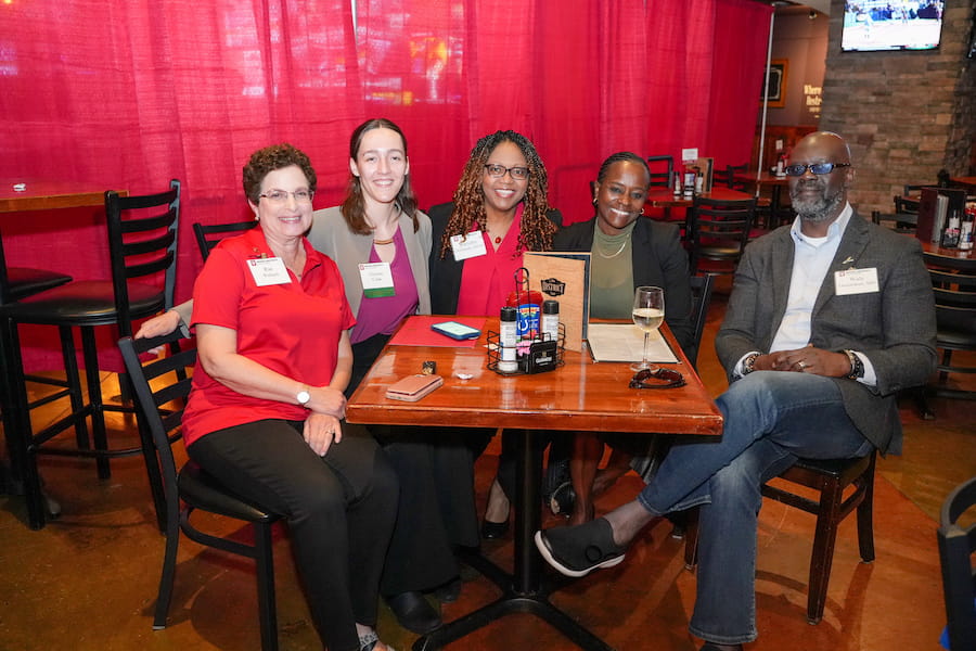 Maryann Chimhanda sits between four other people around a table at The District Tap.