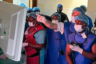 Several people in an operating room with Dr. Al-Haddad pointing to a screen