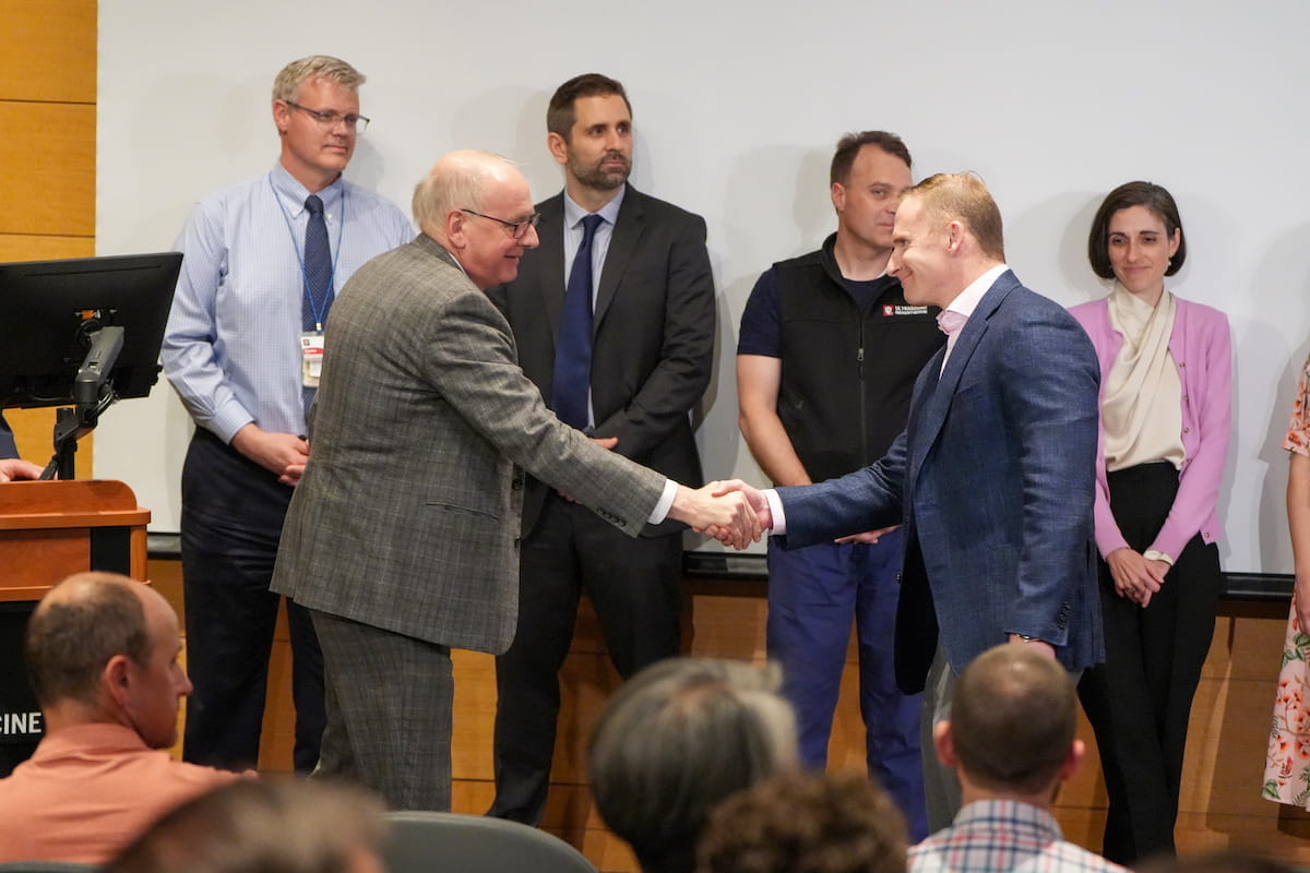 Dean Hess shakes the hand of a Trustees' Teaching Award recipient.