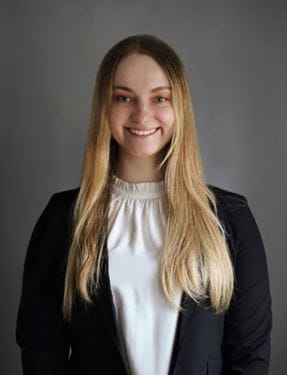 Headshot of Viktoriya Sapkalova (female caucasian with long blonde hair) wearing white blouse and black jacket