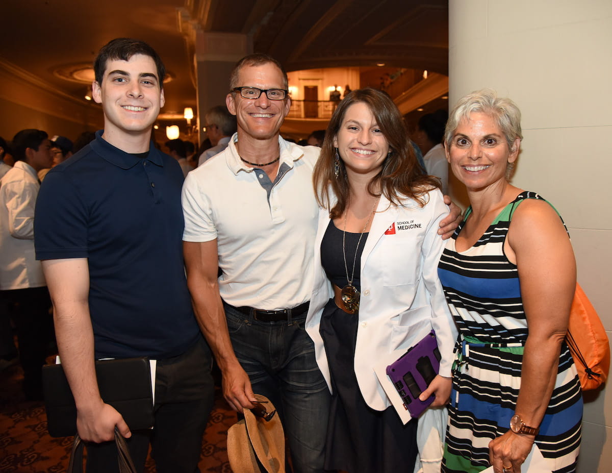 Hannah Kline in her white coat after the ceremony posing with her family, husband Jacob and parents Jeff and Judy Kline