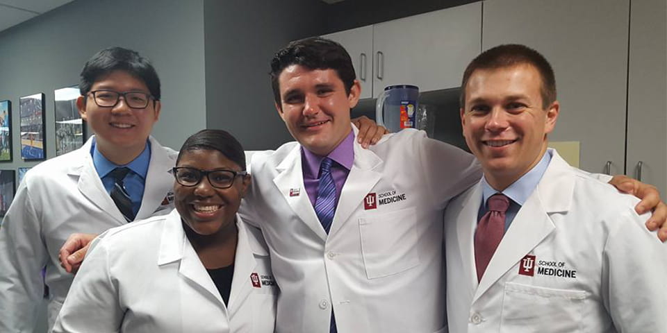 four diverse students in evansville wearing white coats