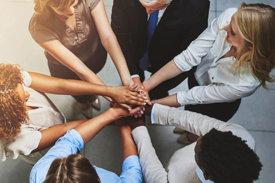 a team of people put their hands together in a group huddle