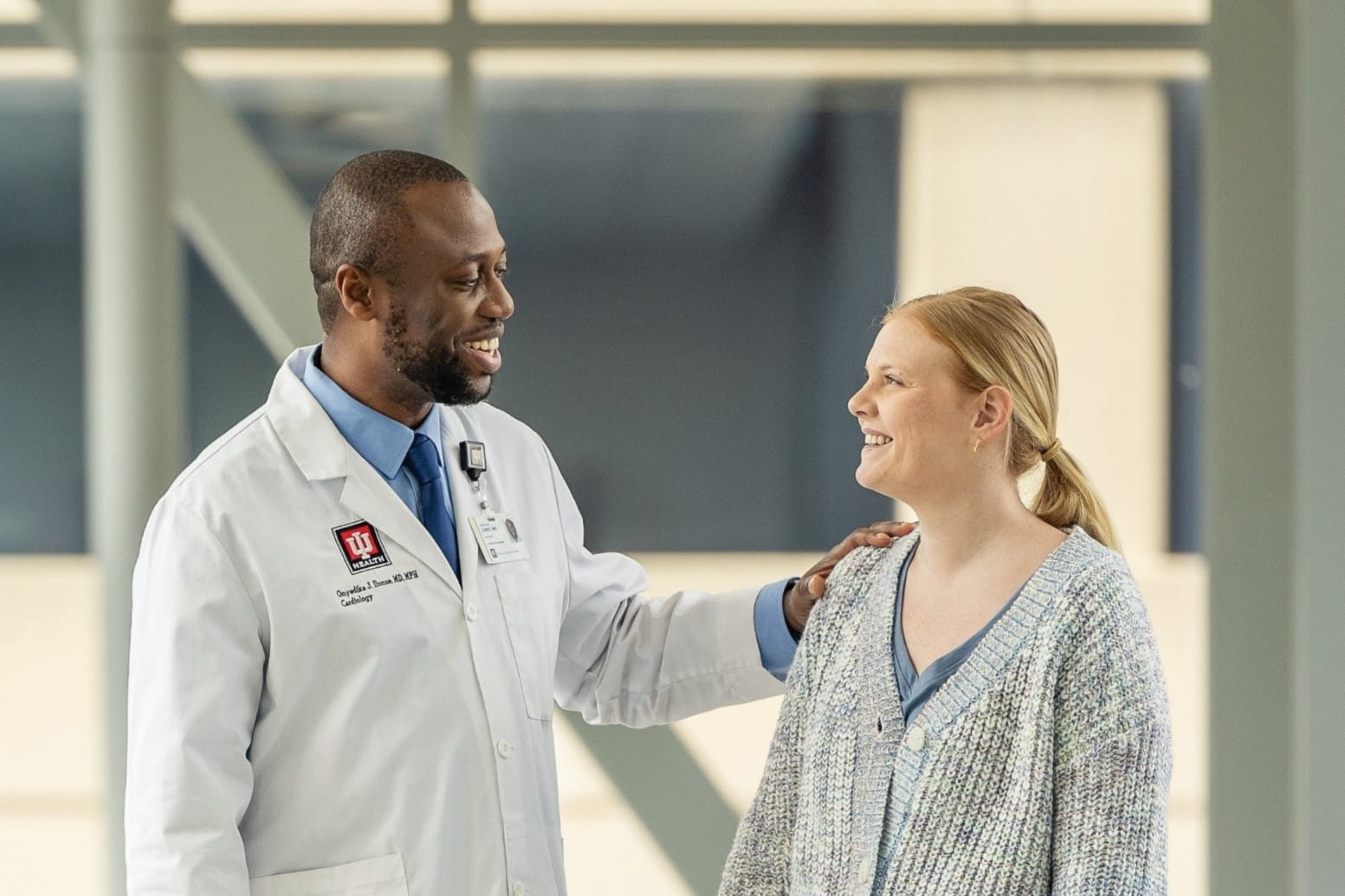 Doctor in white coat consoles patient outside clinic.