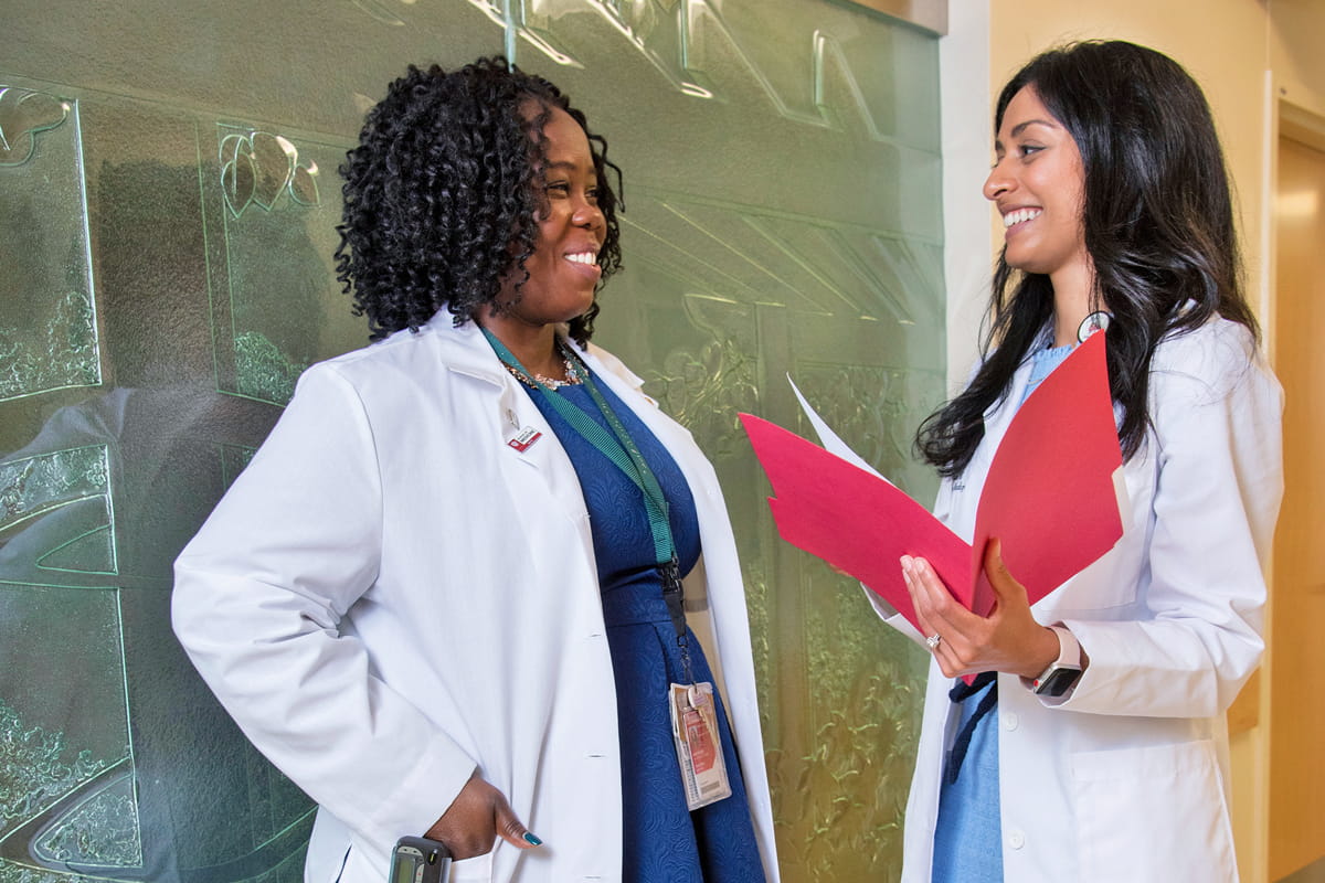 two female physicians speak together about a patient's file