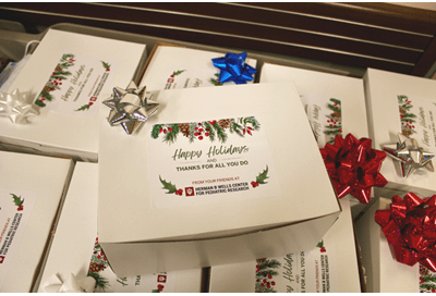 photo of several white donut boxes with festive "happy holidays" stickers and gift bows