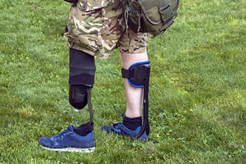 Military individual with a prosthetic leg and a leg support on the other leg.