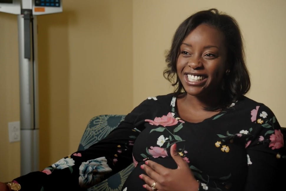 Faith Kuntz smiles and holds her pregnant stomach