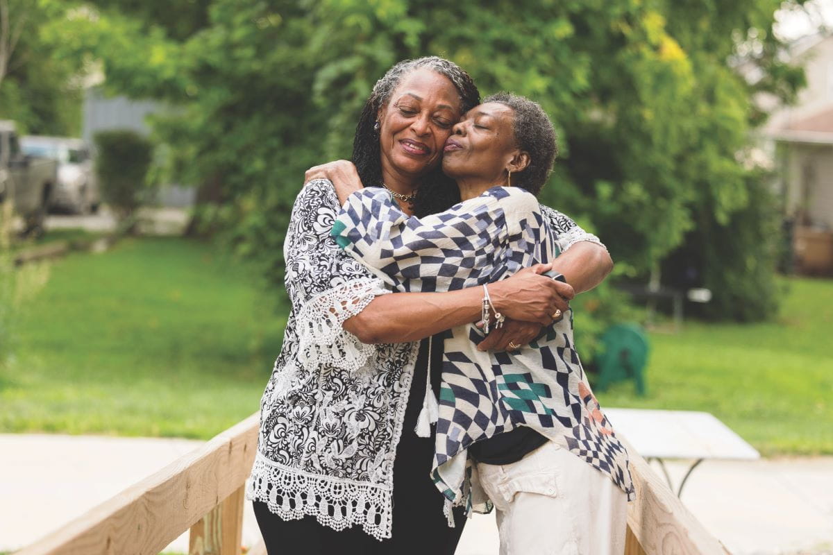 Kathy Lane hugs her sister outside on a summer day
