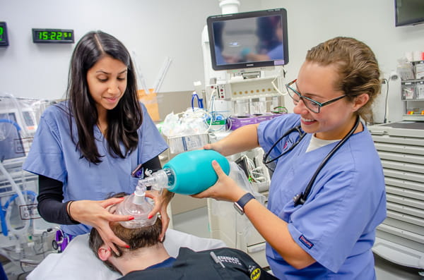 Medical students simulate helping a patient breathe.