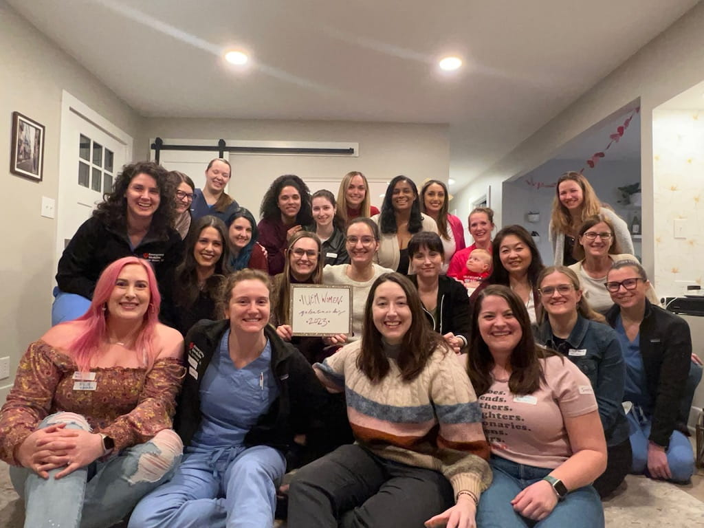 A group photo of women physicians gathered in a living room. 
