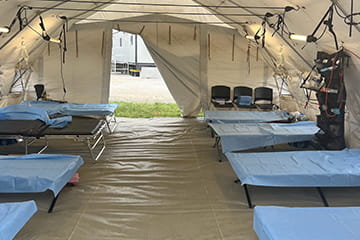 A medical tent set up with empty beds. 