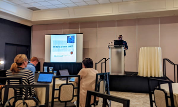 a guest lecturer stands at a podium and speaks to family medicine residents