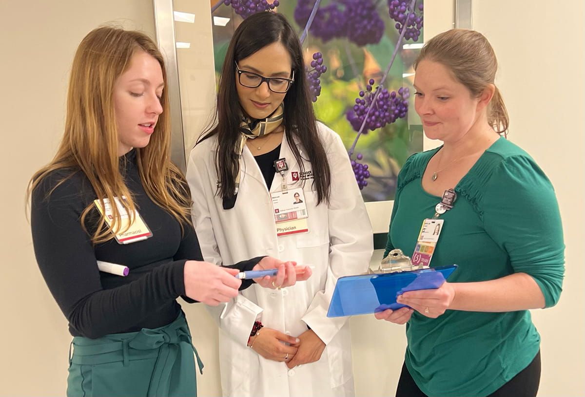 two residents and a faculty member review a patient file together