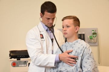 a resident examines a patient in the adult inpatient rotation