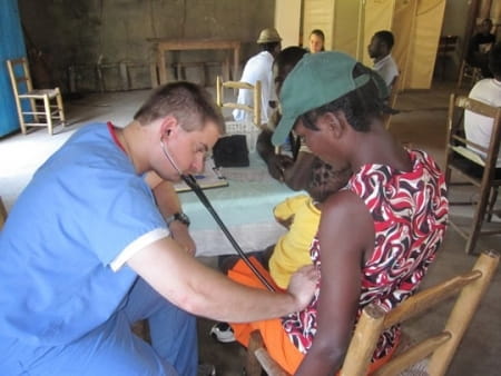 Dave Amrhein examines a mother and child during a medical mission trip to Haiti in 2010.