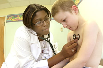 A physician uses a stethoscope to listen to a pediatric patient's heart.