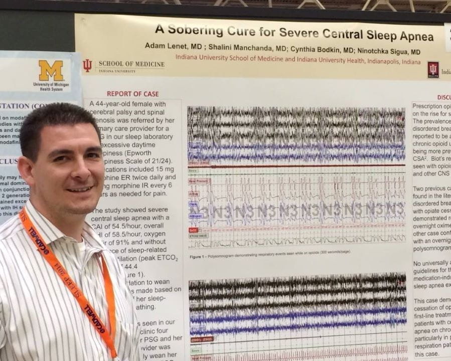 a fellow stands in front of their research poster presentation