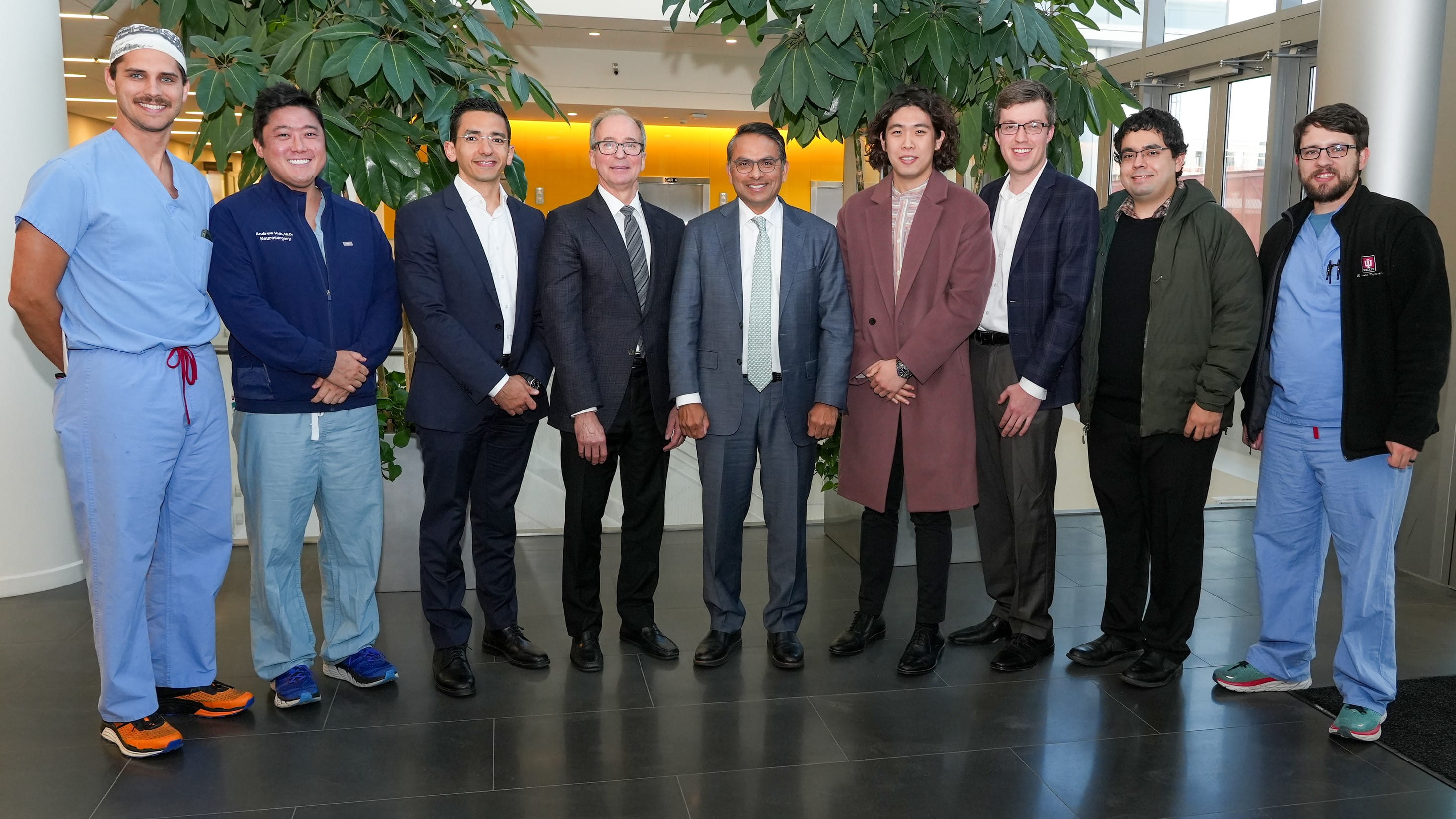 a group of faculty stand between two ferns at a lecture