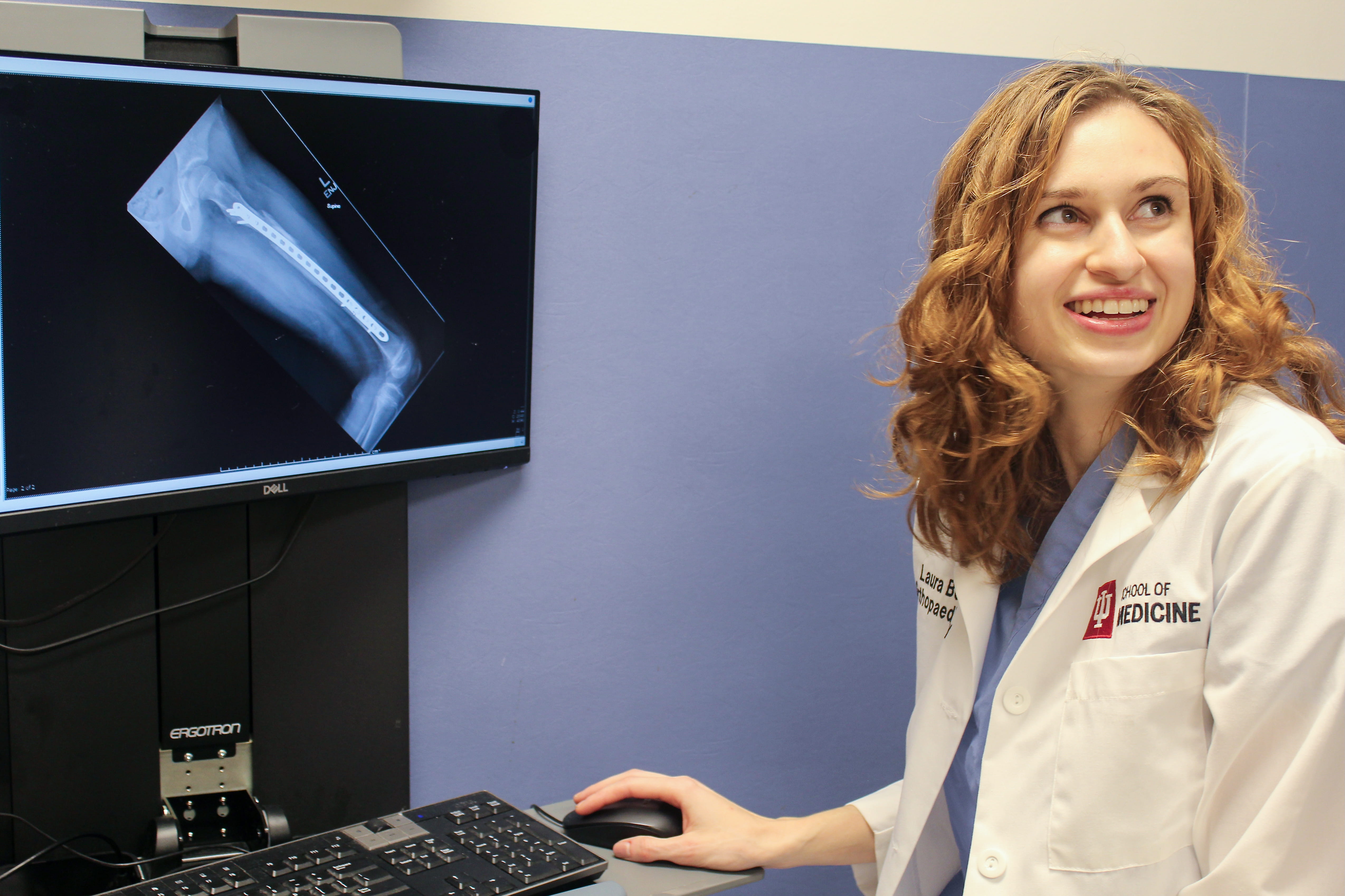 Orthopaedic Surgery Resident Laura Bess, MD, looks over an x-ray on a computer screen in an exam room. 