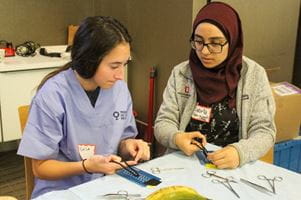 Two female students practice sutures during the 2023 Perry Initiative at IU School of Medicine.