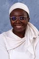Halimat wearing a white top, white head covering and glasses.