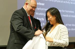 wade clapp gives a white coat to a graduating fellow who is asian american