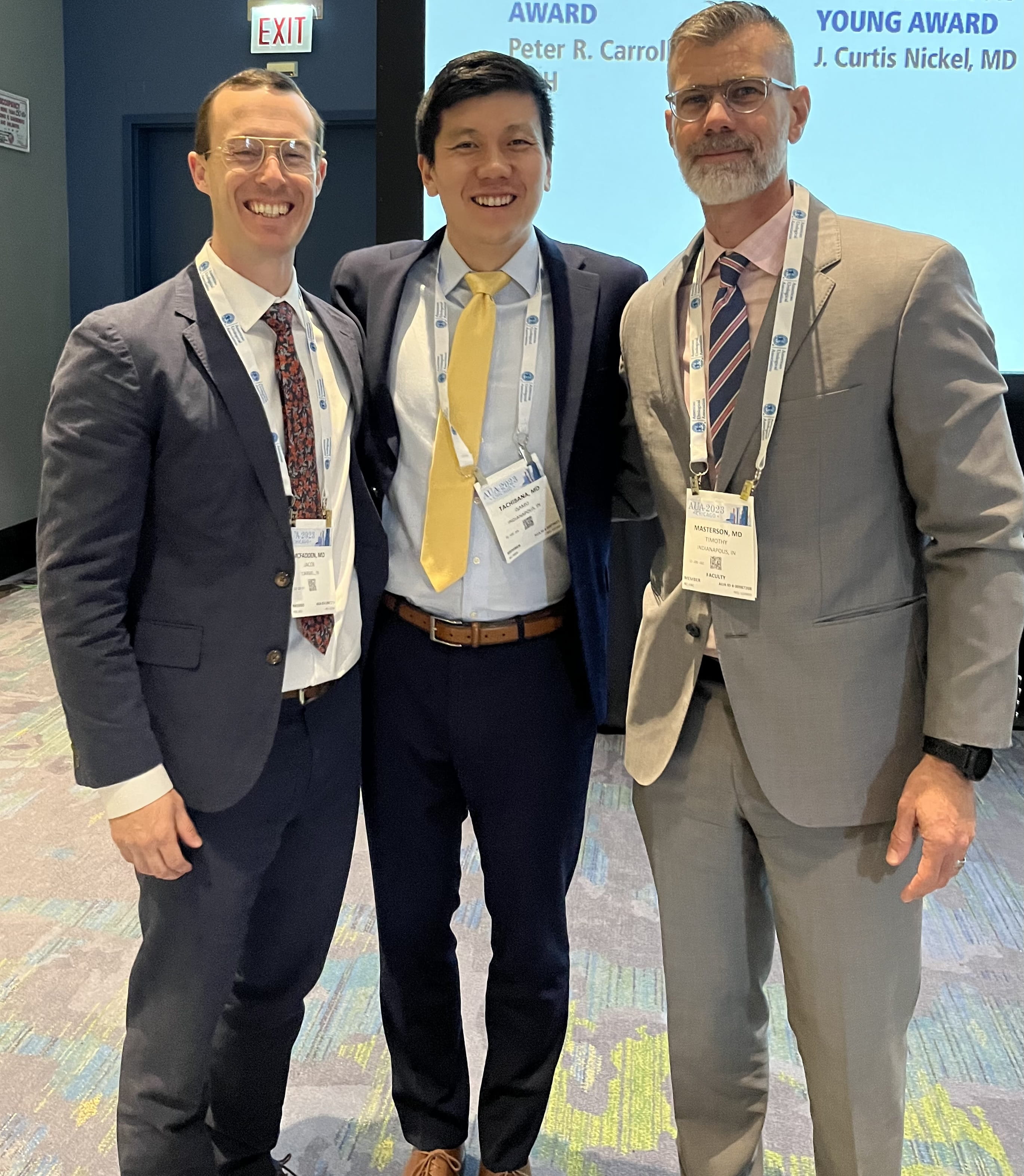 urologic oncology fellow stands smiling with two faculty members
