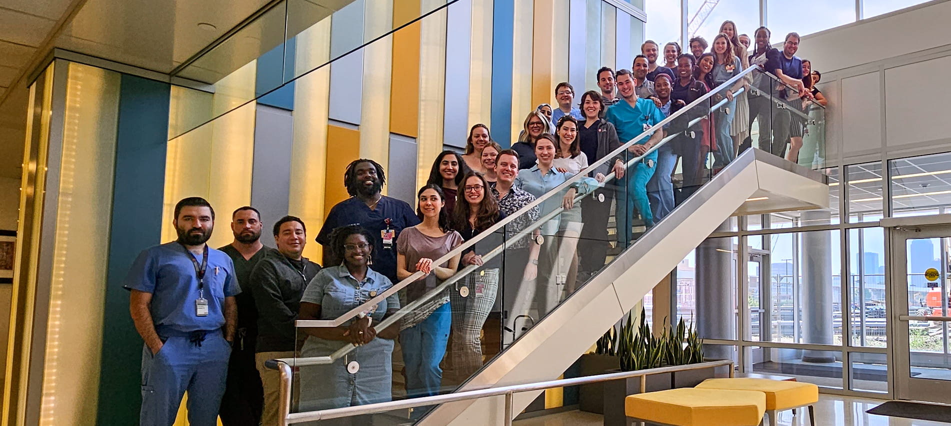 a large, diverse group of psychiatry residents line a staircase for a group photo