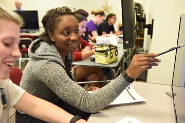 two students work together in front of a computer monitor