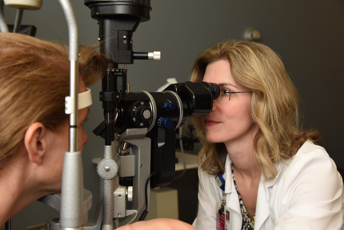 a physician examines a patient's eyes through a piece of equipment