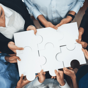 stock photo of 6 individuals holding large puzzle pieces together