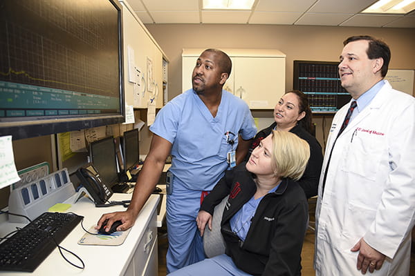 A team of residents and physicians studies a monitor during a patient's labor
