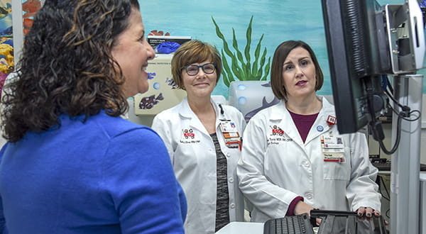 Three female members of the Pediatric Urology team at IU School of Medicine look at a computer monitor