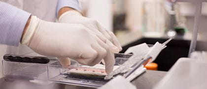 a close up shot of gloved hands working with samples in a lab