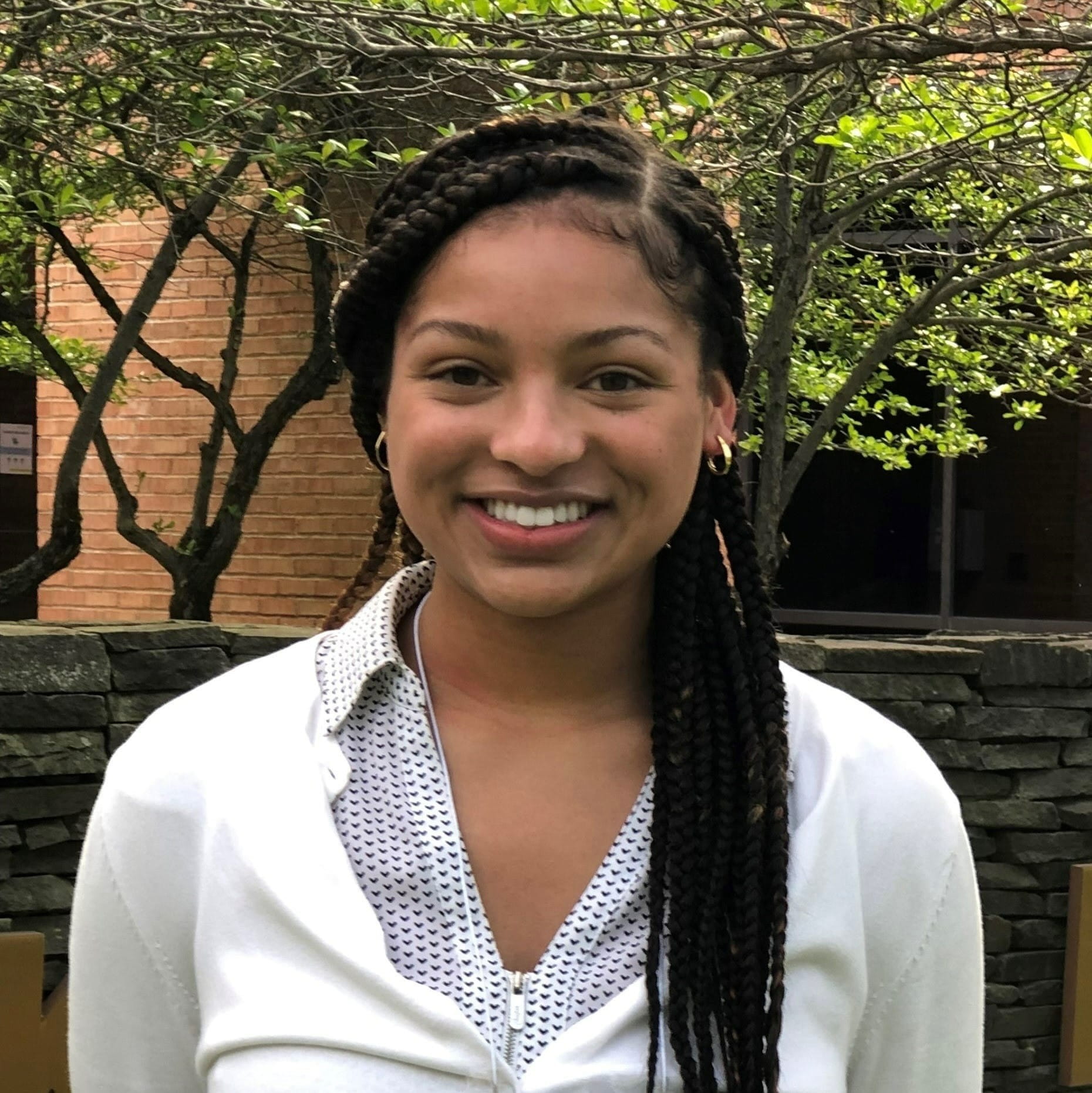 jayla french stands outside for a photo. she has long dark braids and is wearing a white sweater